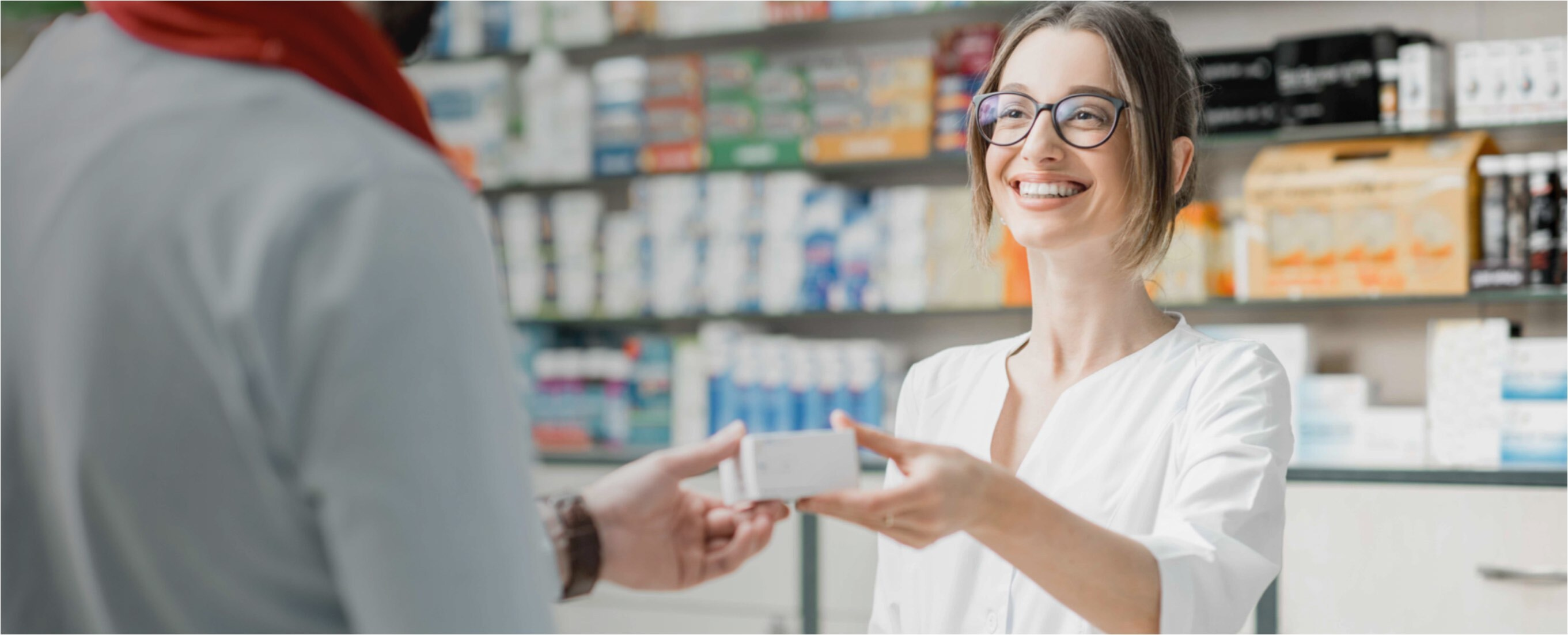 Mujer sonriente cogiendo un producto de la mano de un farmacéutico